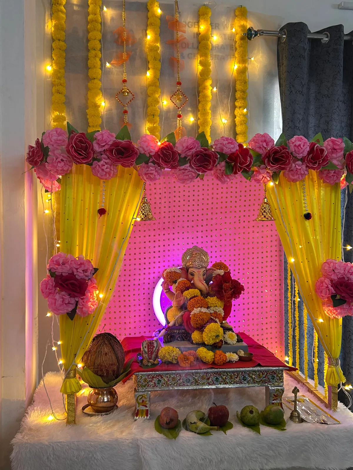Ganpati shrine decorated with marigold garlands, roses and lights